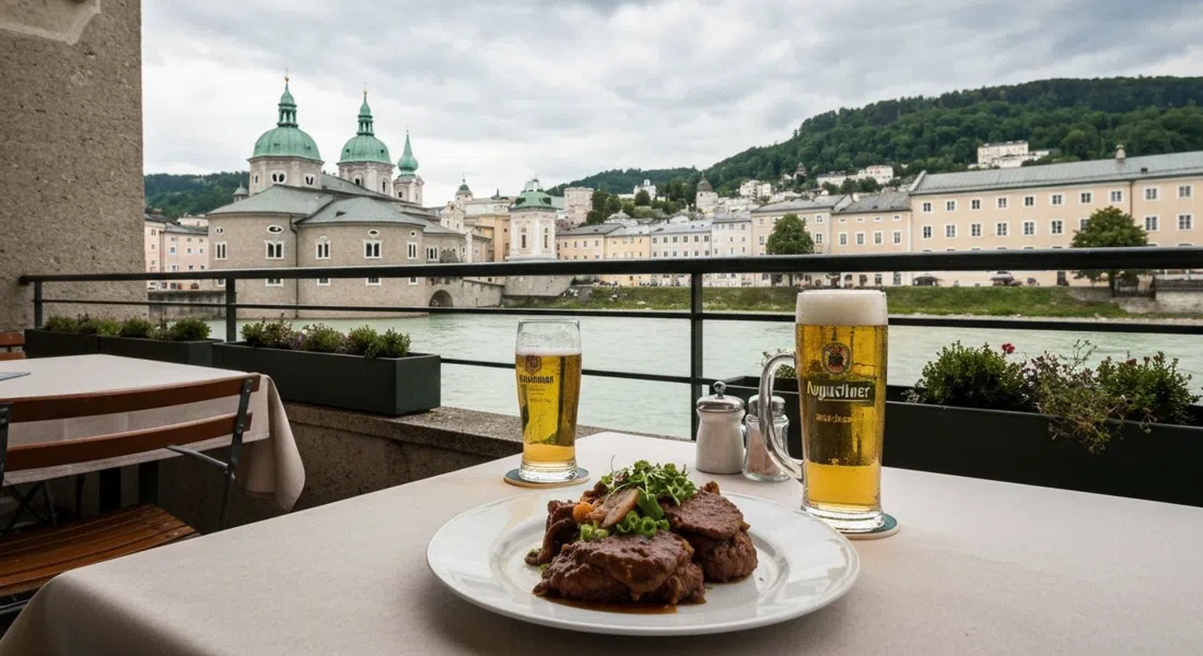 una mesa de terraza en Bärenwirt en Müllner Hauptstraße 8, Backhendl servido y un vaso de cerveza Augustiner con el Salzach y el Kapuzinerberg al fondo